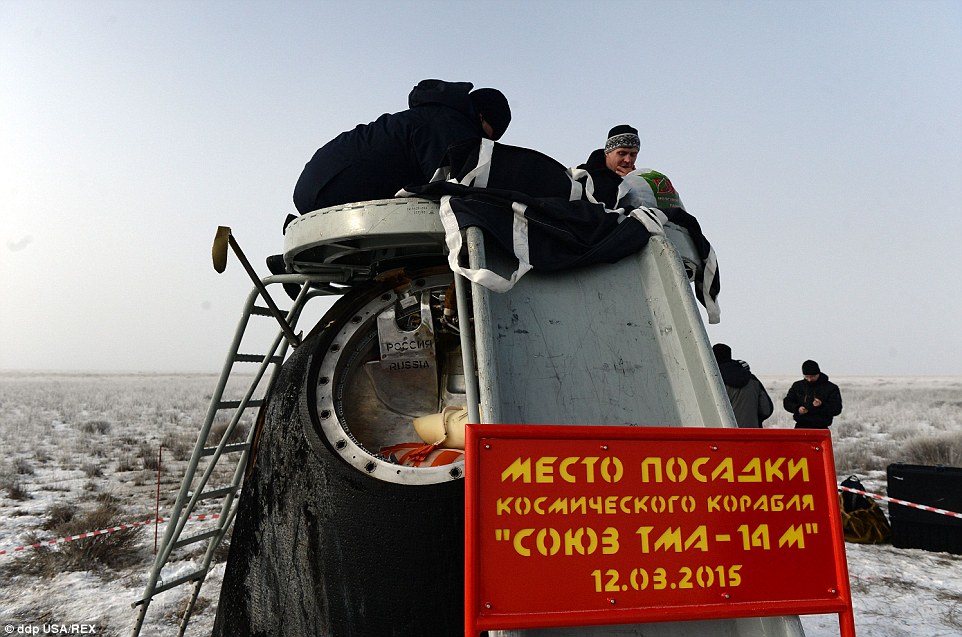 Russia's space agency ground personnel check the Soyuz TMA-14M capsule shortly after the landing
